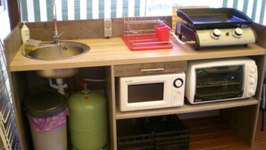 Une petite cuisine équipée d’un évier, d’un grille-pain, d’un four à micro-ondes et d’une bouteille de gaz.
