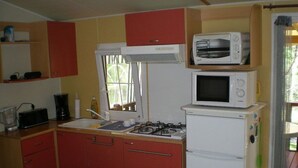 Une cuisine de taille réduite équipée d’une cuisinière à gaz, d’un four à micro-ondes et d’un réfrigérateur.