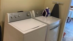 A laundry room with two white washing machines and an ironing board. - Nice to meet you (Jackson)