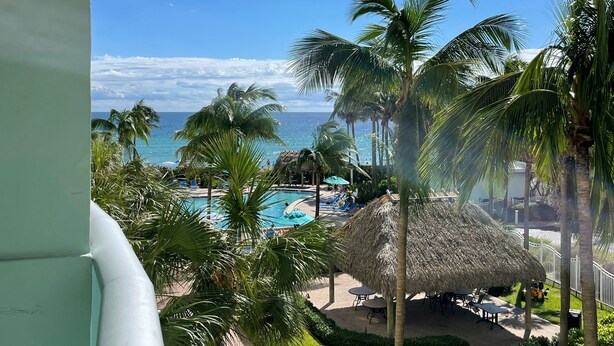 A resort with a pool, palm trees, and a view of the ocean. - Tropical ocean view one bedroom (Hollywood)