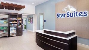 Zona de recepció d'un hotel amb el rètol de StarSuites, una taquilla i un bar de tapes amb diferents plats.