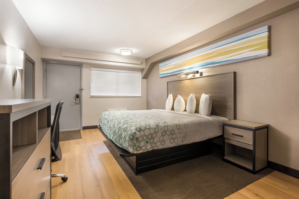 Un dormitorio moderno con cama, mesitas de noche, un escritorio y una silla.