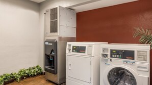A laundry area with a water dispenser and two front-loading washing machines. - HomeTowne Studios By Red Roof Princeton – Ewing/ Lawrenceville (Lawrenceville)