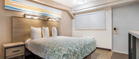 A hotel room with a bed, bedside tables, a headboard, a window with blinds, and a door.