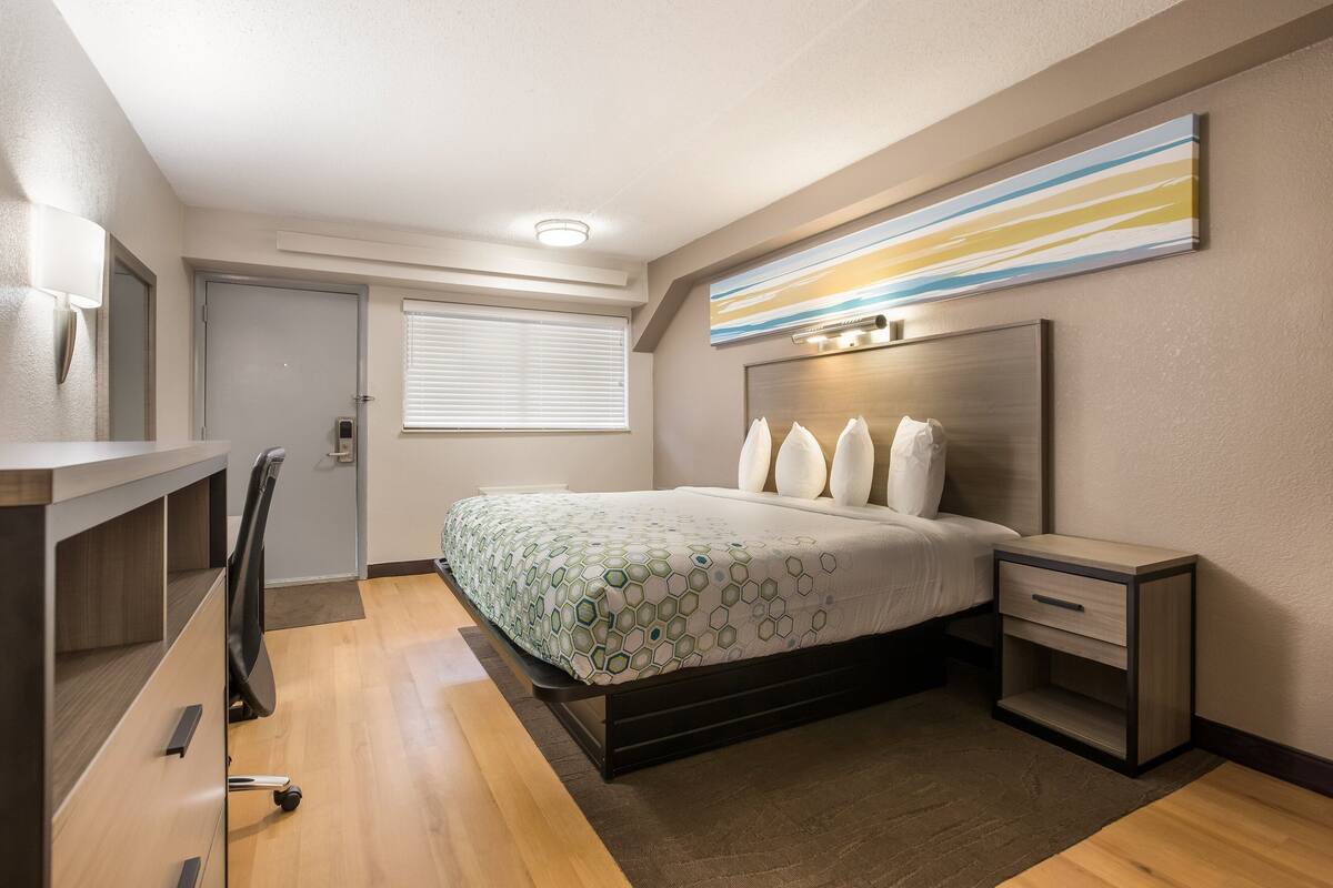A modern bedroom with a bed, bedside tables, a desk, and a chair.