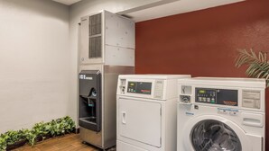 Un cuarto de lavandería con dispensador de agua, dos lavadoras apiladas y una pared roja.