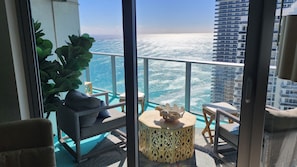 A balcony with a view of the ocean, wicker furniture, and a decorative table.
