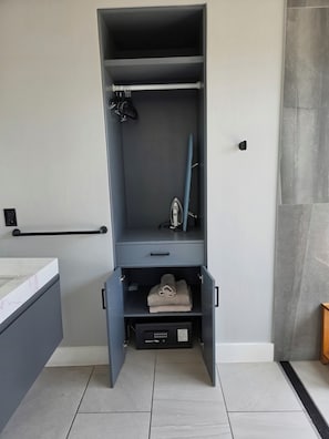 A bathroom with a grey cabinet, a towel rack, and a shower area.