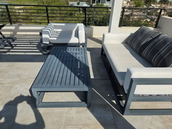 A rooftop terrace with a seating area featuring a sofa and a table.