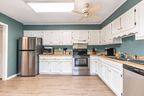 Enjoy cooking in this well-lit kitchen with a refrigerator, oven, and cabinetry.