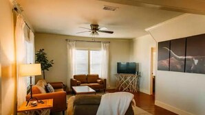A living room with a sofa, a coffee table, a TV, and a ceiling fan.