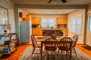 Enjoy meals in this kitchen with a dining table and chairs, a small island with a sink, and a refrigerator.