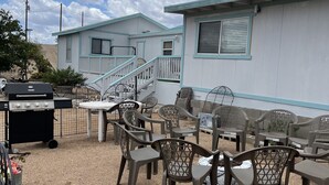 A patio area with outdoor furniture, a barbecue grill, and a small building with a staircase. - Family Style Lake House (Meadview)