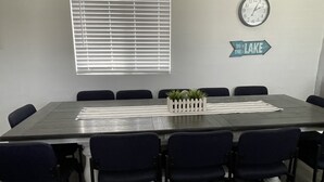 A conference room with a long table, eight chairs, a clock, and a sign pointing to the lake. - Family Style Lake House (Meadview)