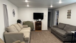 A living room with two sofas, a TV, and a bookshelf. - Family Style Lake House (Meadview)