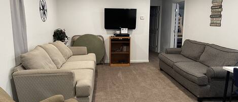 Una sala de estar con dos sofás, un televisor y una estantería.
