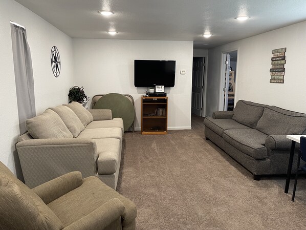 A living room with two sofas, a TV, and a bookshelf. - Family Style Lake House (Meadview)