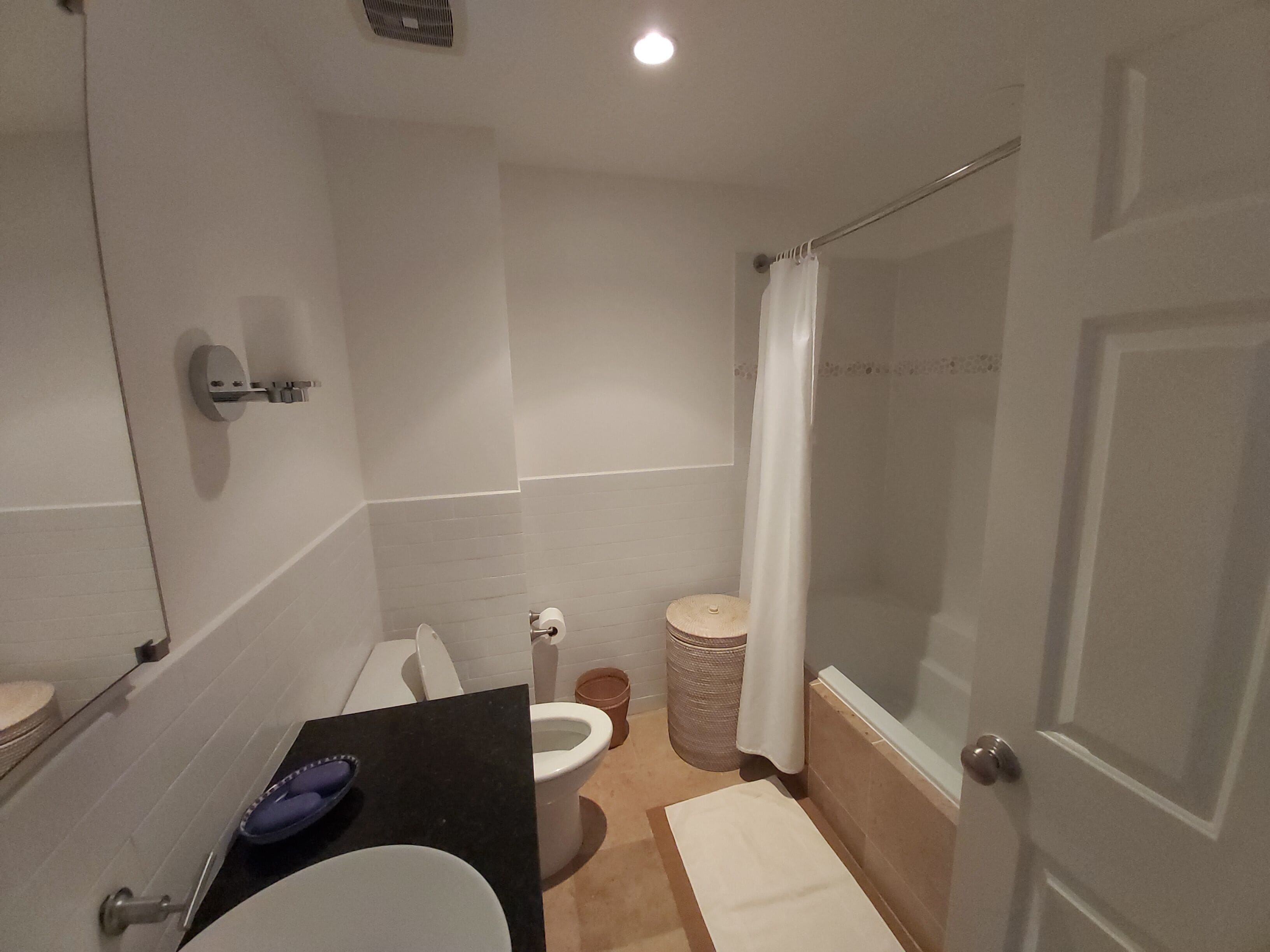 Un baño con inodoro, lavamanos y zona de ducha.