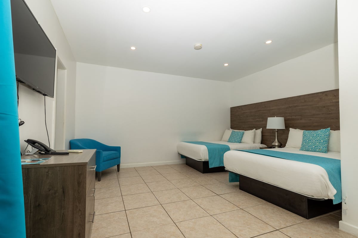 Une chambre d’hôtel avec deux lits, un bureau, une chaise et un téléviseur.