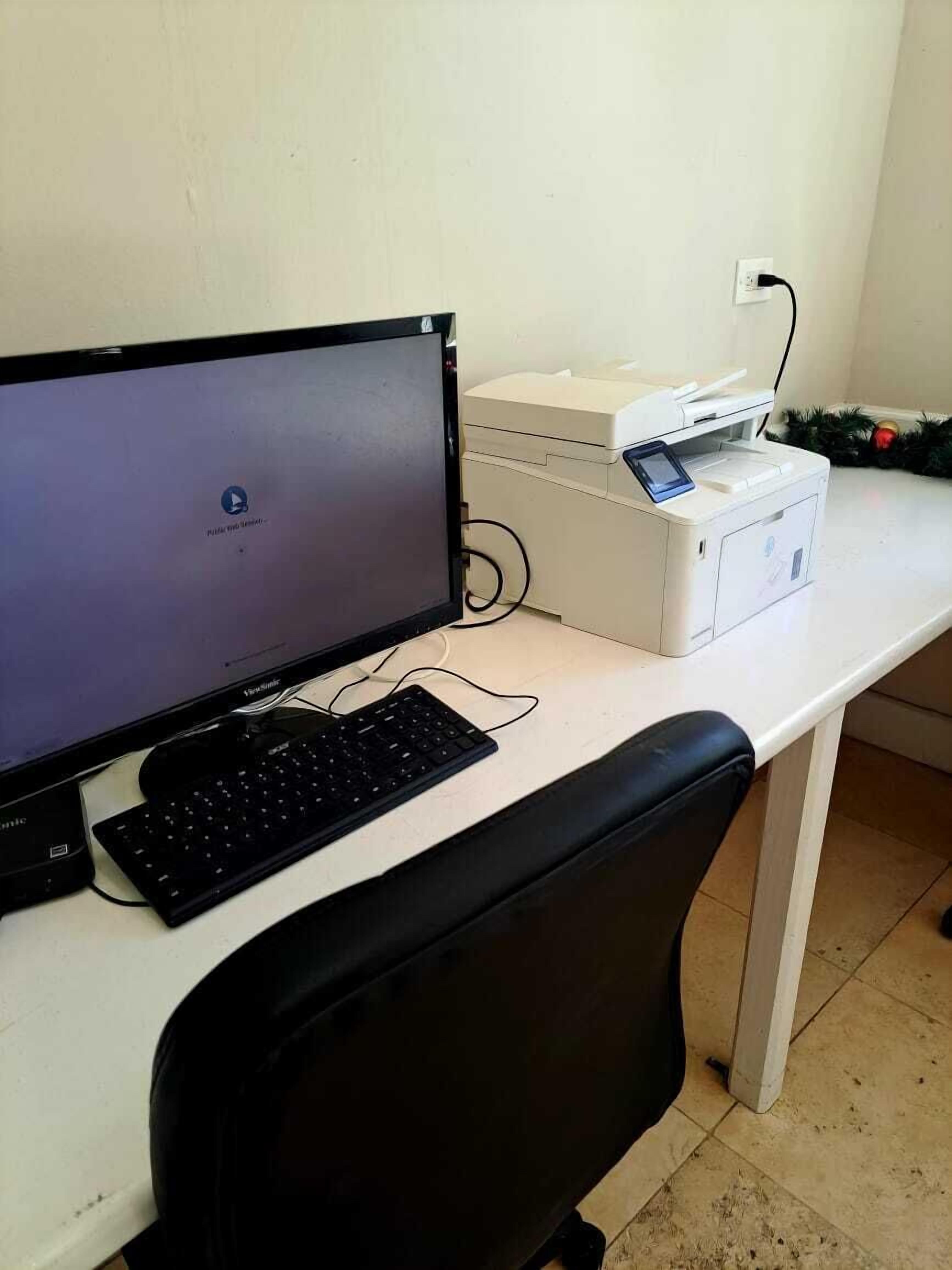 A computer desk with a monitor, keyboard, and printer.