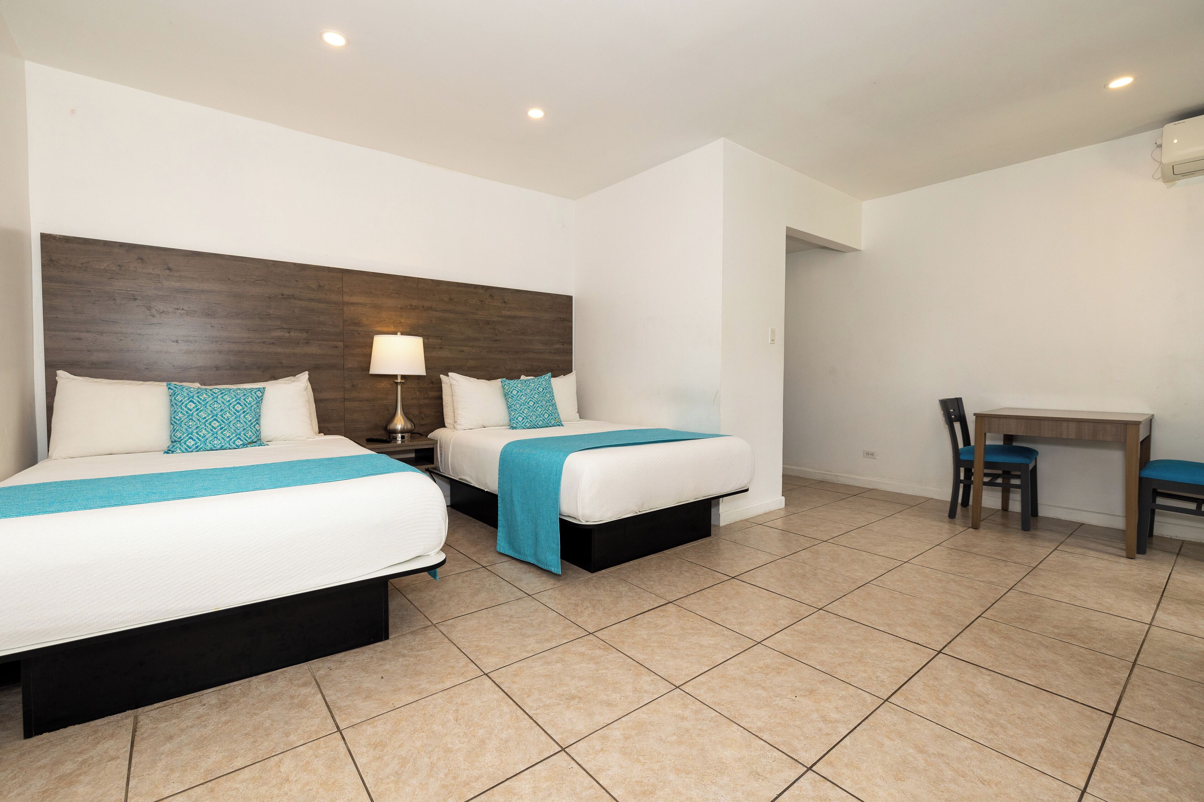 A hotel room with two beds, a desk, and a chair.