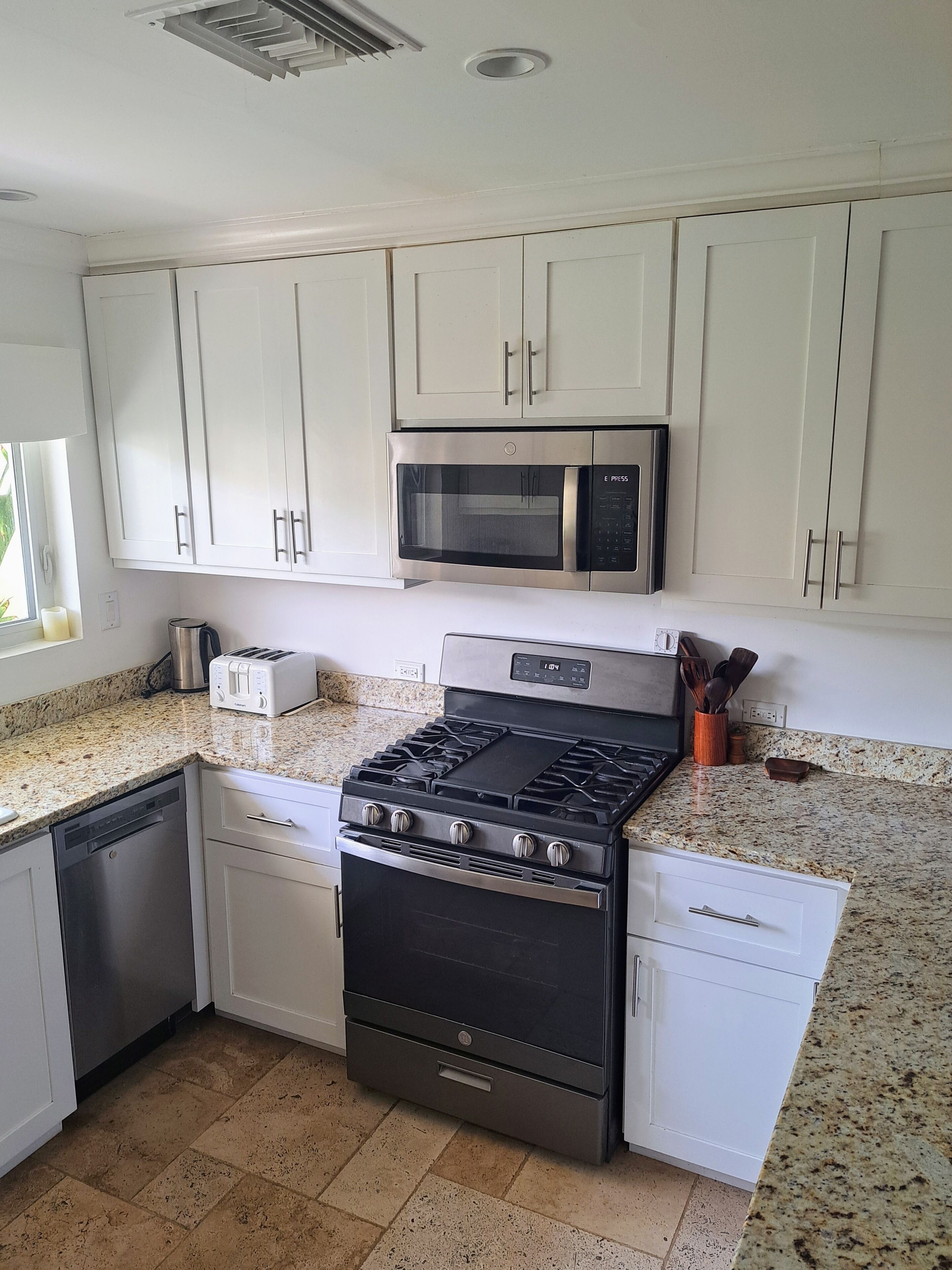 A kitchen with white cabinets, a microwave, a stove, and a toaster.