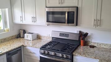 A kitchen with white cabinets, a microwave, a stove, and a toaster.