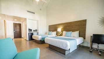A hotel room with two beds, a kitchenette, a bathroom, and a seating area.