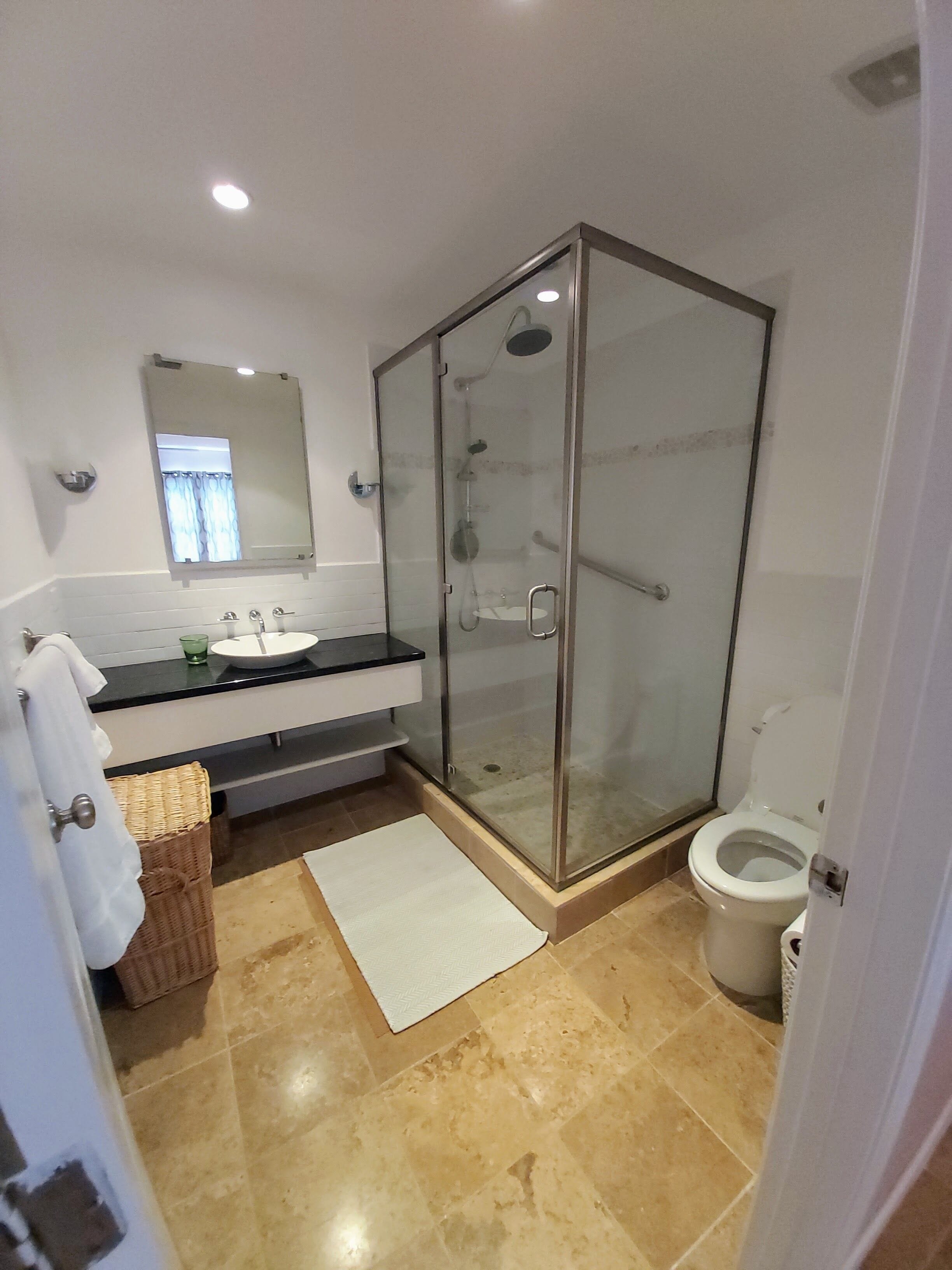 A bathroom with a glass-enclosed shower, a white sink, and a toilet.