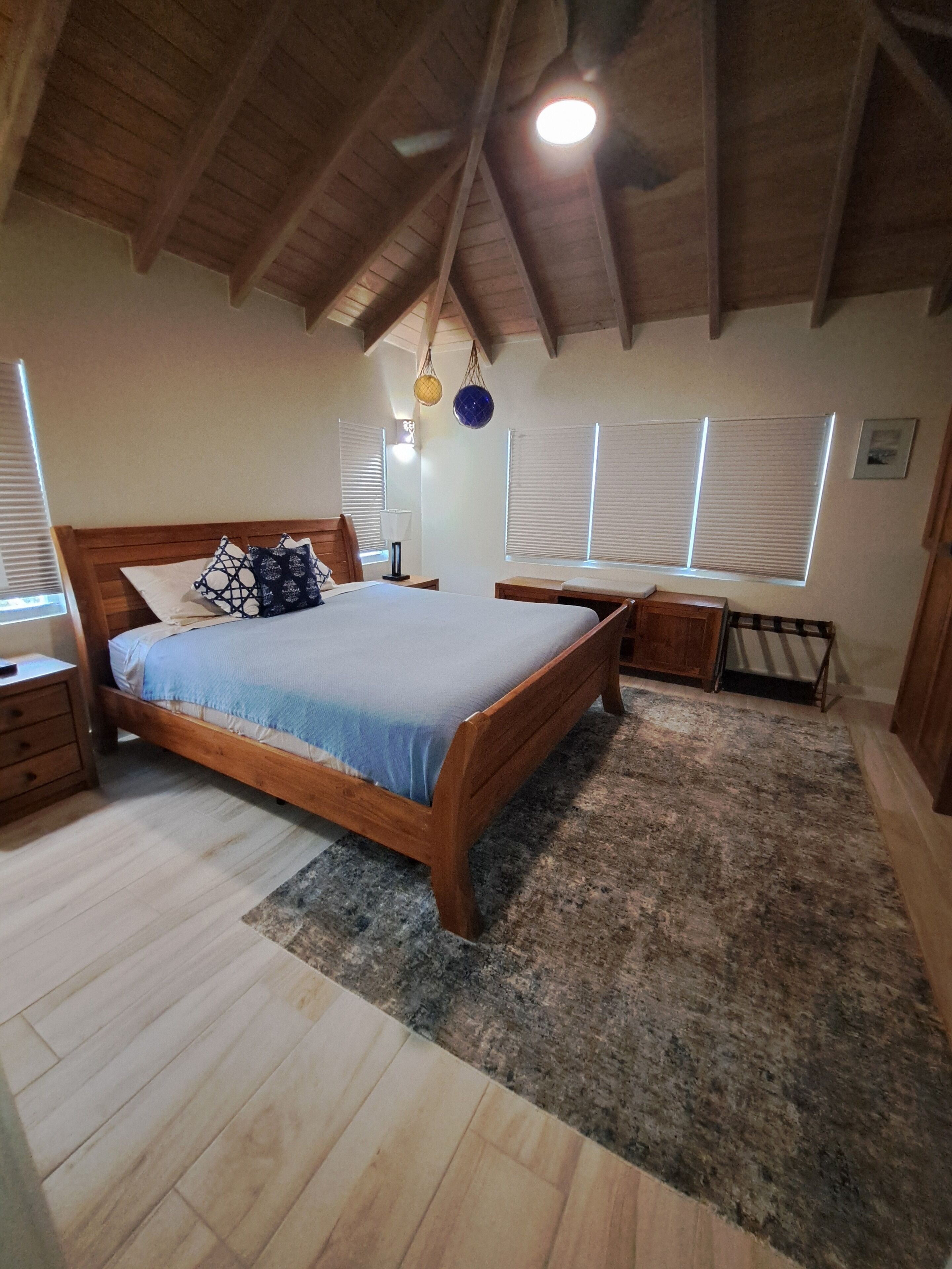 Quarto com cama de madeira, mesa de cabeceira e ventoinha no teto.