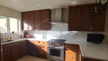 Una cocina moderna con armarios de madera, estufa de acero inoxidable y salpicadero de azulejos.
