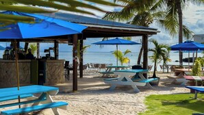Een café aan het strand met terras, een bar en uitzicht op zee.
