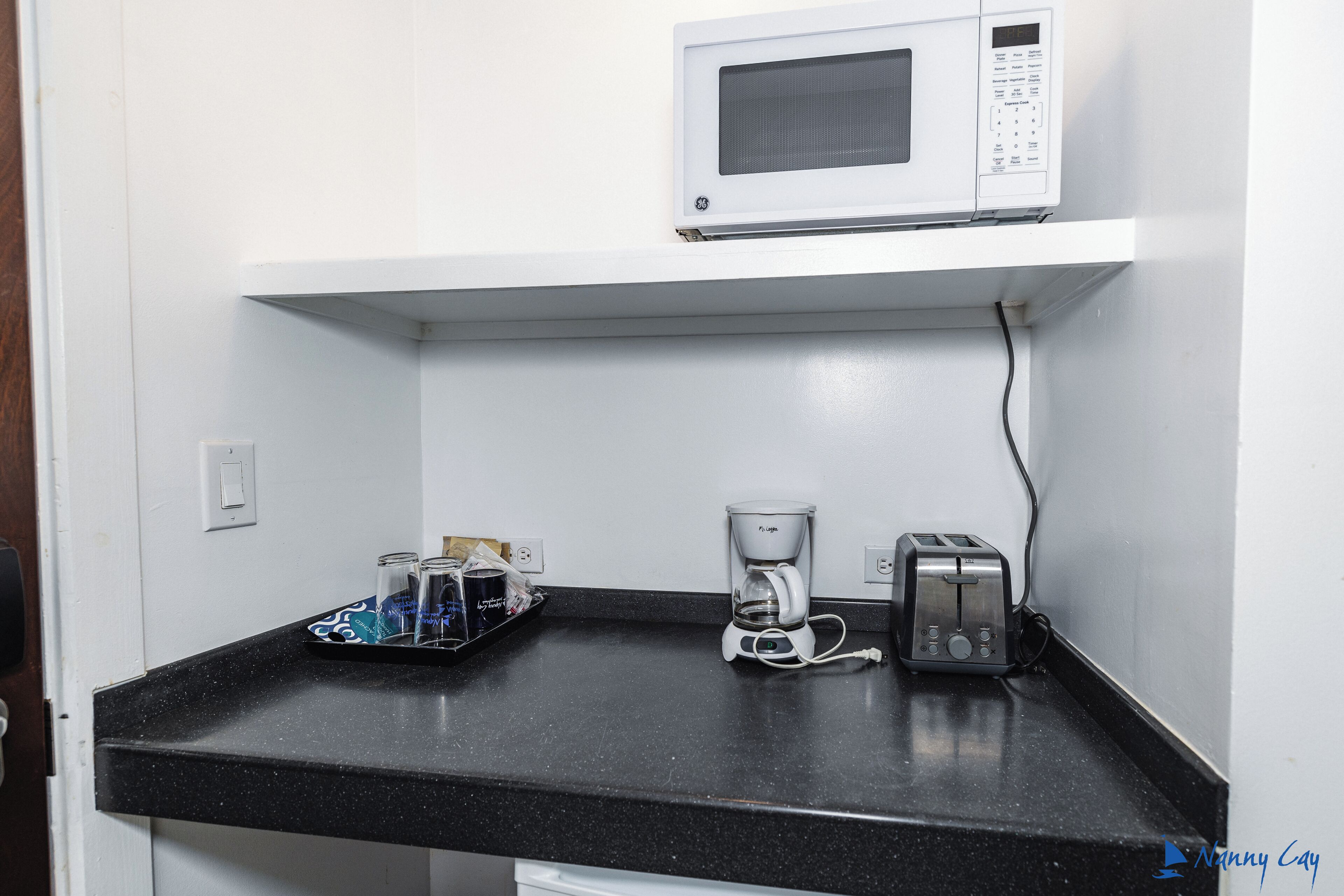 A kitchen with a microwave, coffee maker, and toaster on the counter.