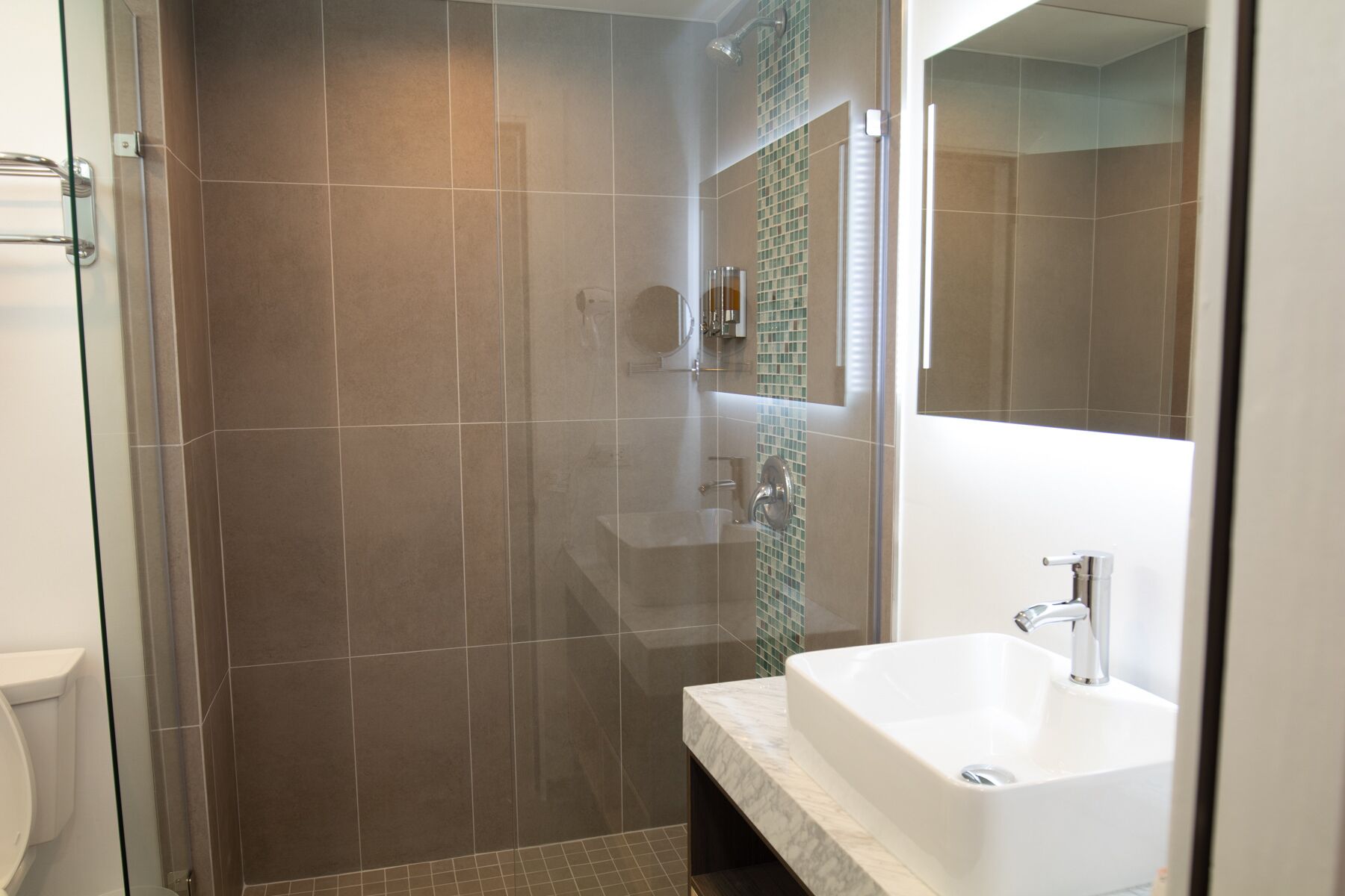 A bathroom with a shower, a sink, and a mirror.