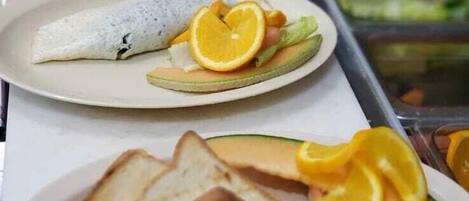 Un bufé de desayuno con diversos platos, como tortillas, tostadas y fruta.