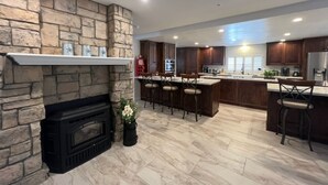Une cuisine moderne avec un mur d’accent en pierre, une cheminée et un coin bar avec des tabourets.