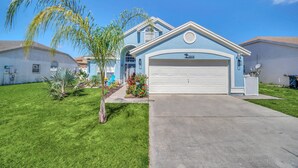 A two-story house with a garage, a well-maintained lawn, and a small garden with various plants. - Welcome to Alena's Place! Only minutes away from Disney! (Kissimmee)