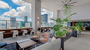 A modern hotel lobby with seating areas, a bar, and a view of the city skyline. - Gorgeous Studio in Downtown Miami - #1911 (Miami)