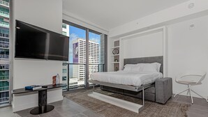 A modern bedroom with a bed, a TV, a desk, and a chair. - Gorgeous Studio in Downtown Miami - #1911 (Miami)