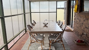 A covered patio with a rectangular table and wicker chairs, a patterned rug, and a brick floor. - Captain's Quarters ~ Pet Friendly - Off Peak Special! (Point Turton)