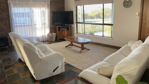 A living room with a sofa set, a television, and a large window with a view of the outdoors. - Captain's Quarters ~ Pet Friendly - Off Peak Special! (Point Turton)