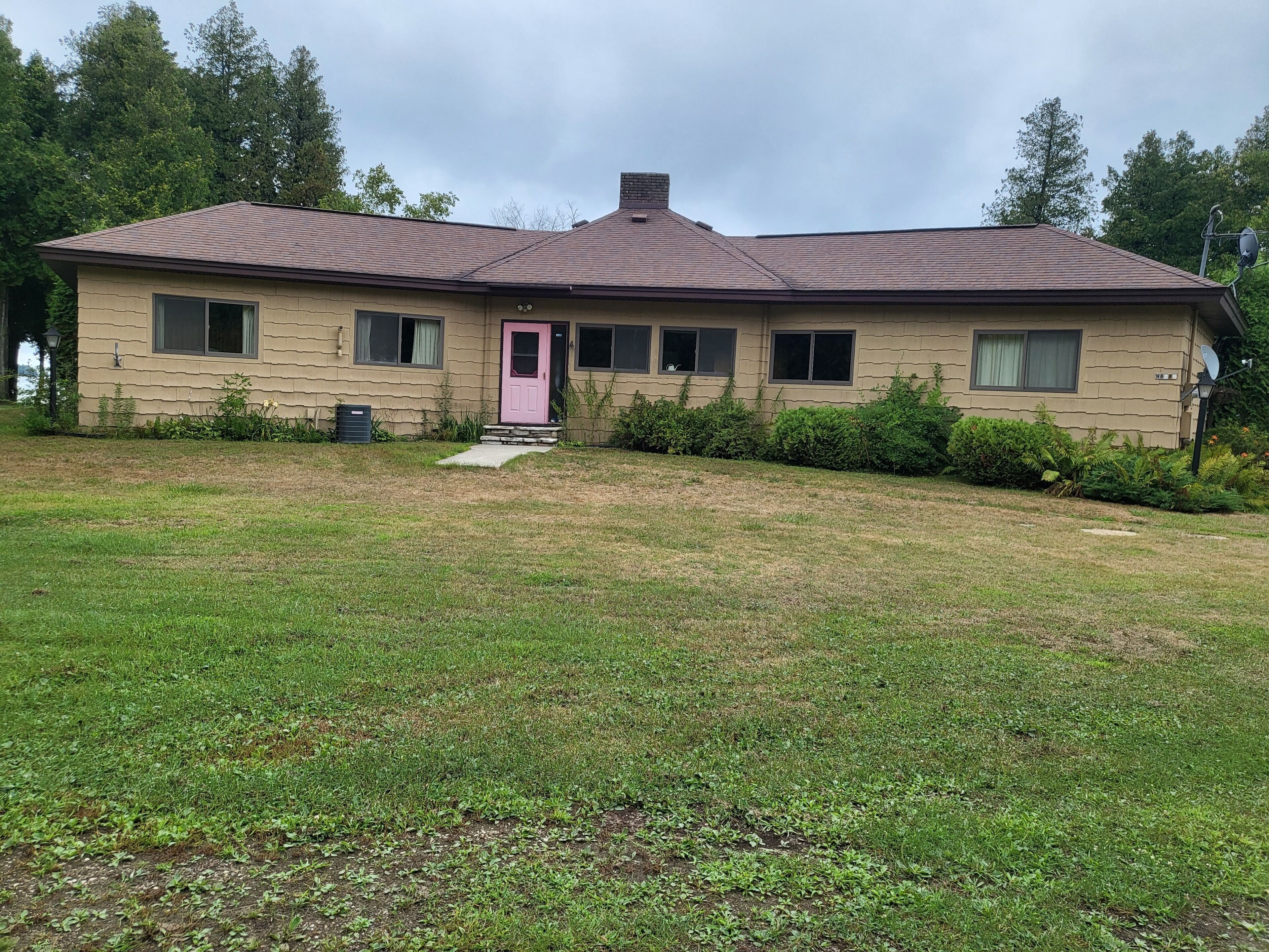 A single-story house with a sloped roof, a pink front door, and a small front porch.