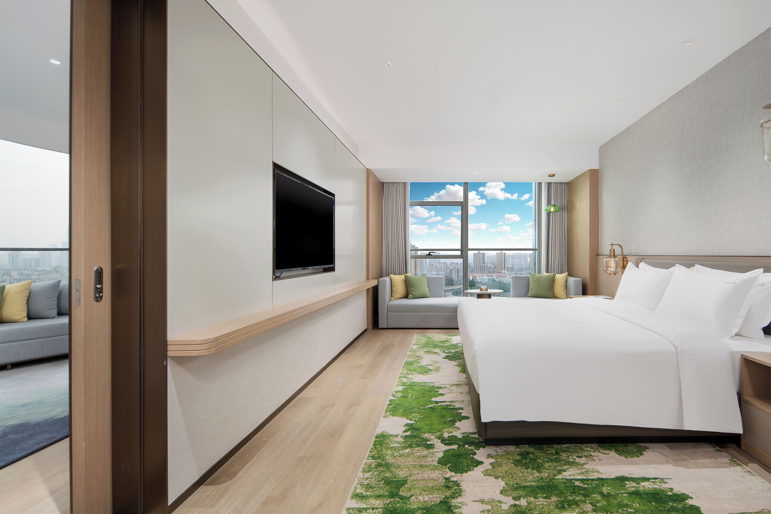 Habitación de hotel moderna con una cama grande, un televisor de pantalla plana, un sofá y vistas a la ciudad.