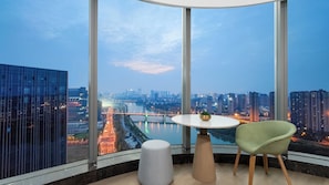 A modern room with a large window, a round table, a green chair, and a small stool. - Holiday Inn Changsha Malanshan by IHG (Changsha)
