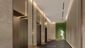 A modern hallway with a marble floor, recessed lighting, and a green accent wall with a white sculpture. - Holiday Inn Changsha Malanshan by IHG (Changsha)