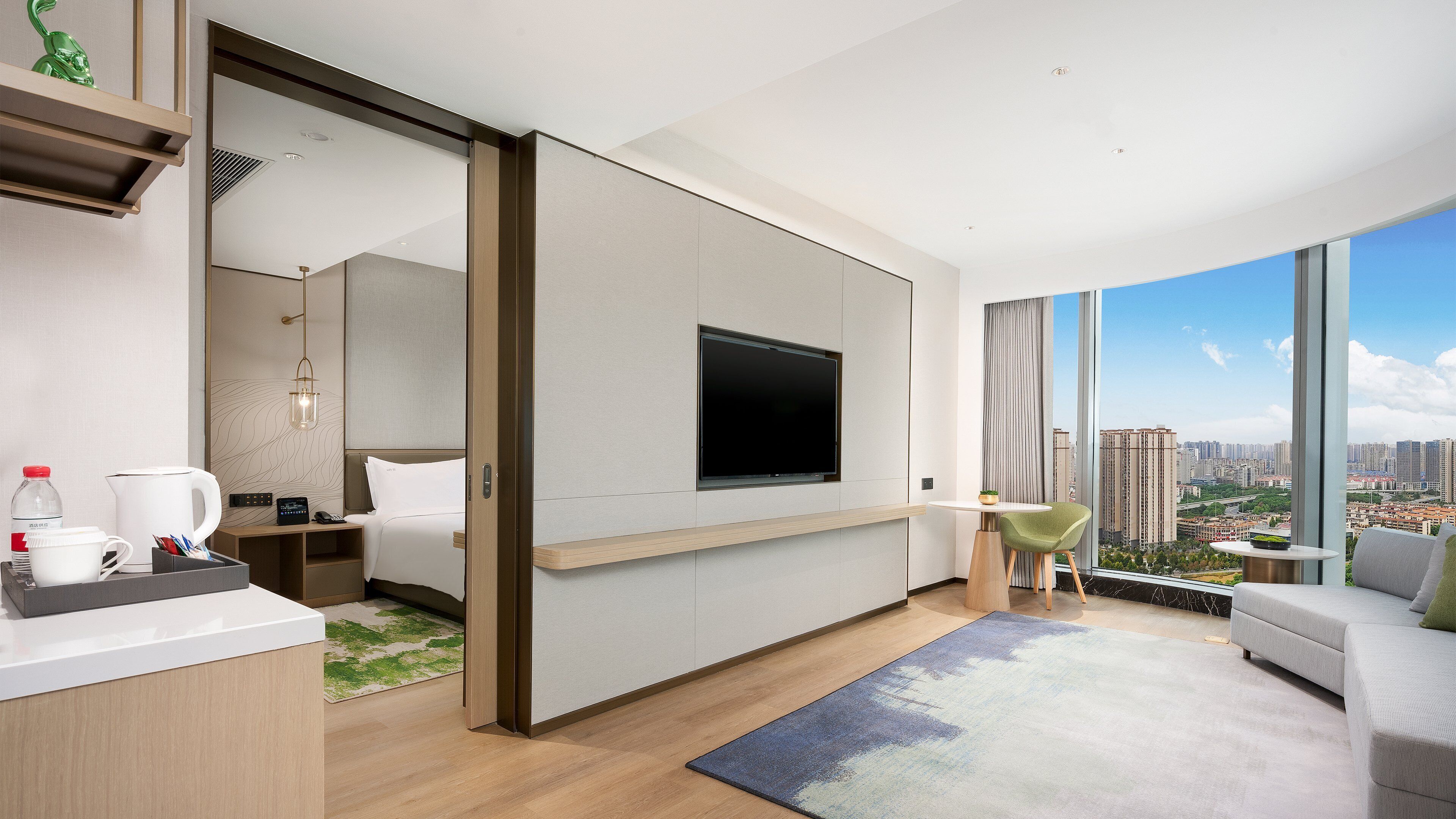 Una habitación de hotel moderna con cama, mesita de noche, televisor y vista a la ciudad.