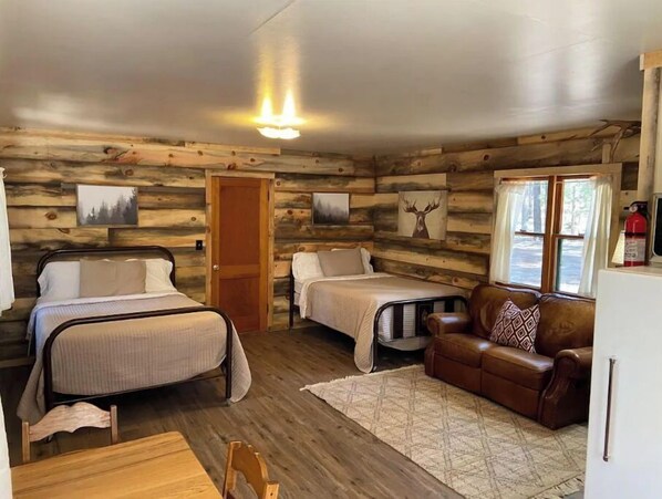A cabin with two beds, a sofa, and a dining table.