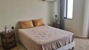 A bedroom with a bed, a ceiling fan, an air conditioning unit, a nightstand, a window with curtains, and a tiled floor. - SPECTACULAR SEA VIEW WITH TERRACE ON BALBOA AV (Panama City)