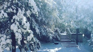 A snow-covered outdoor area with a wooden staircase leading up to a building. - Hot Tub Hideaway  (Idyllwild-Pine Cove)