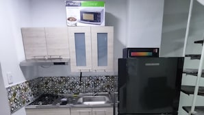 Una cocina pequeña equipada con refrigerador, microondas y pileta.